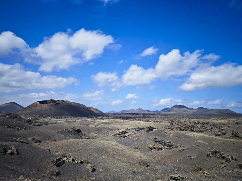 Black lava fields of Timanfaya National Park under a wide blue sky