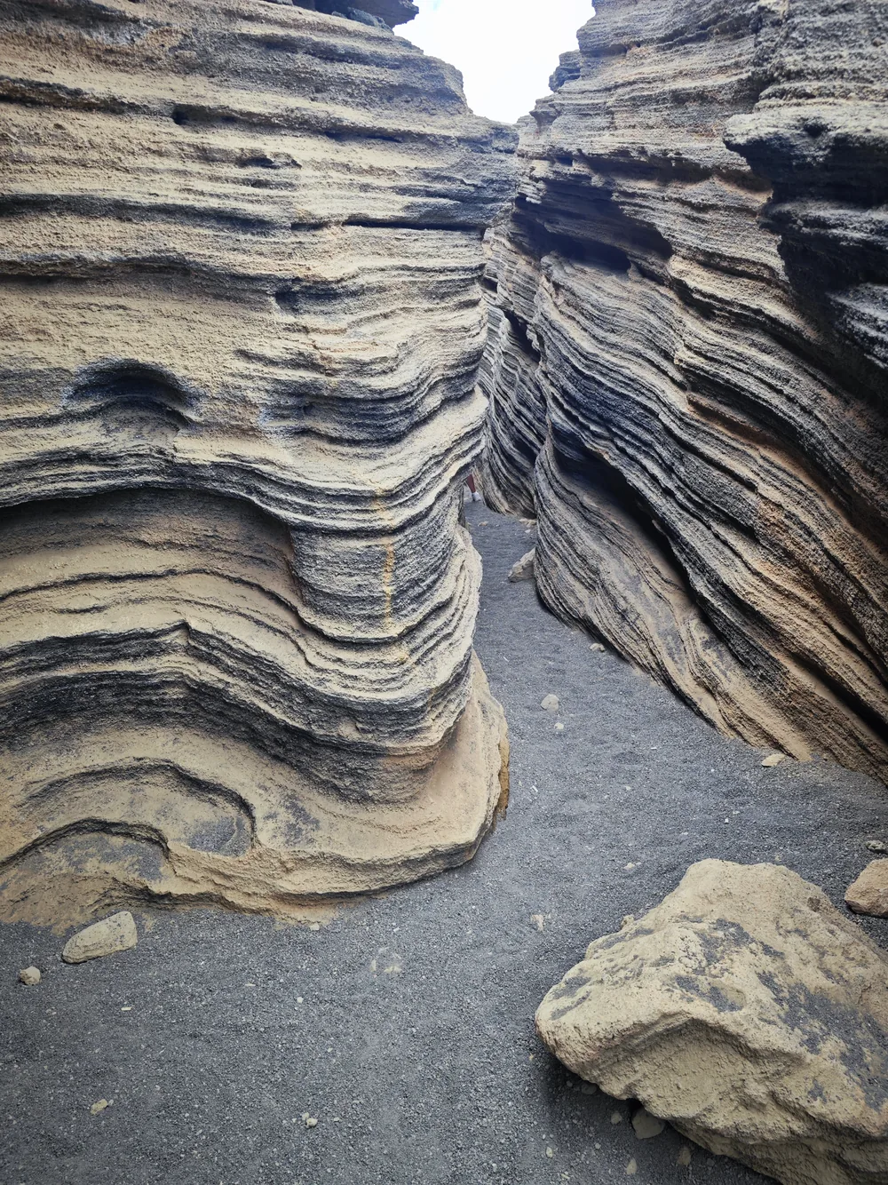 Narrow canyon between layered black and ochre lava walls