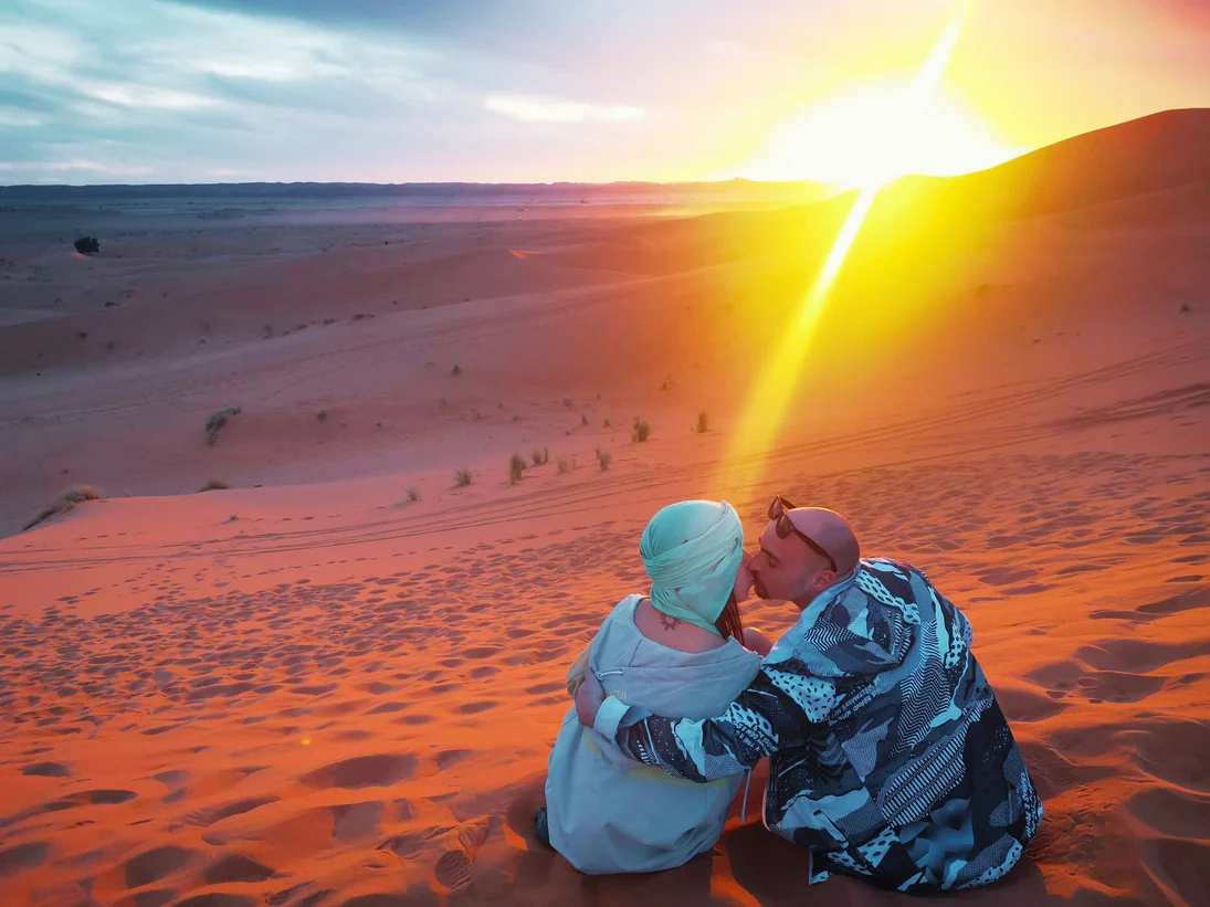 The couple sharing a sunset kiss in the desert