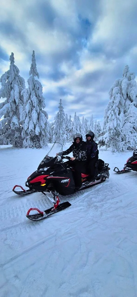 The couple on a snowmobile in a snowy forest